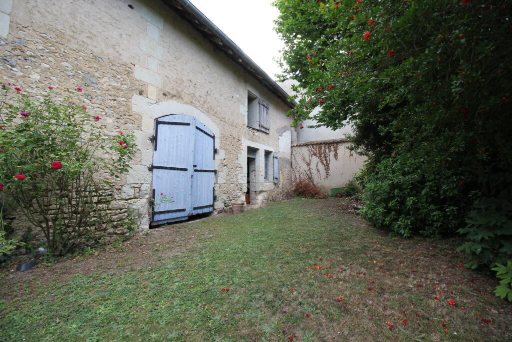 Maison rustique avec jardin et porte bleue.