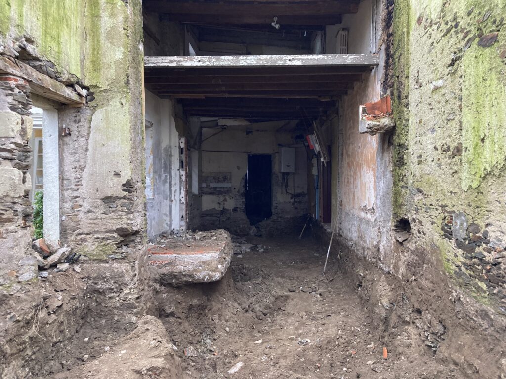 Intérieur de maison en ruine avec mousse et débris.